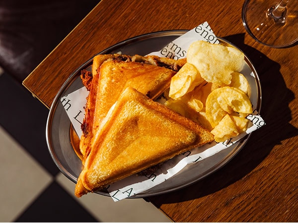 The filthy-good cheese toastie on offer at Arm's Length served with a pile of salty crisps.