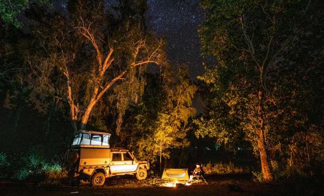 A 4WD is parked by a campfire under the stars at Lorella Springs Wildnerness on the Savannah Way, Northern Territory. (Image: Tourism NT/Sean Scott)