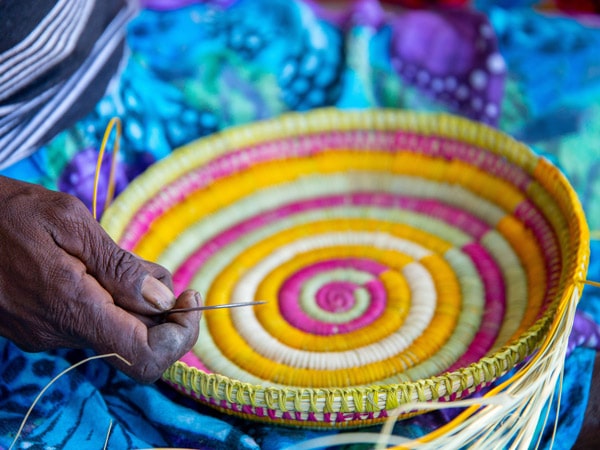 an artist weaving a basket at the Injalak Arts and Crafts Centre