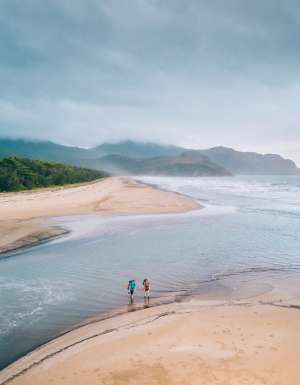 Two people crossing a beach along the Thorsborne Trail