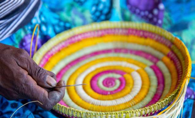 an Indigenous artist weaving a basket at the Injalak Arts and Crafts Centre