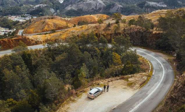 An aerial view of a car with people next to a winding road in Queenstown, Tasmania. (Image: Jason Charles Hill)