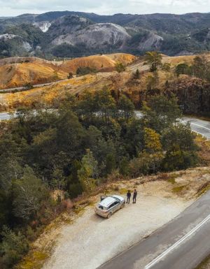 An aerial view of a car with people next to a winding road in Queenstown, Tasmania. (Image: Jason Charles Hill)