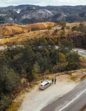 An aerial view of a car with people next to a winding road in Queenstown, Tasmania. (Image: Jason Charles Hill)
