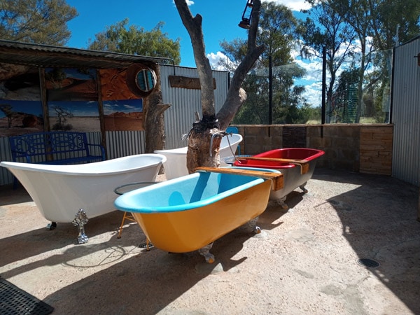 A series of four coloured baths sit outside in the Queensland outback town of Eulo. (Image: Artesian Mud Baths)