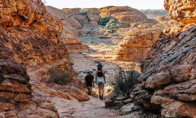 Man and woman trekking across Kings Canyon. (Image: Tourism NT and Jess Caldwell & Luke Riddle)