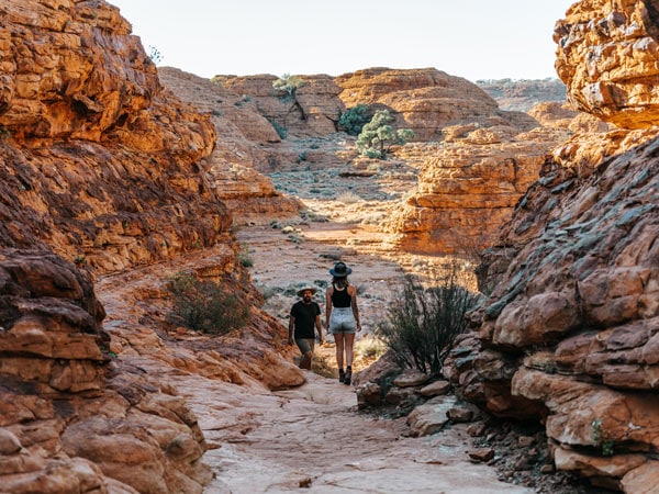 Man and woman trekking across Kings Canyon. (Image: Tourism NT and Jess Caldwell & Luke Riddle)