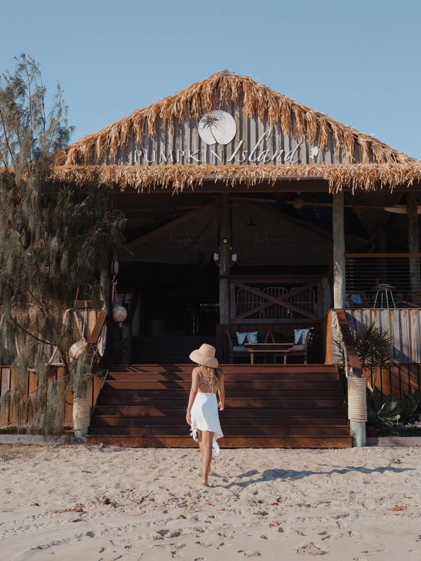 Lady walking in to the main area of Pumpkin Island. (Image: Tourism and Events Queensland)