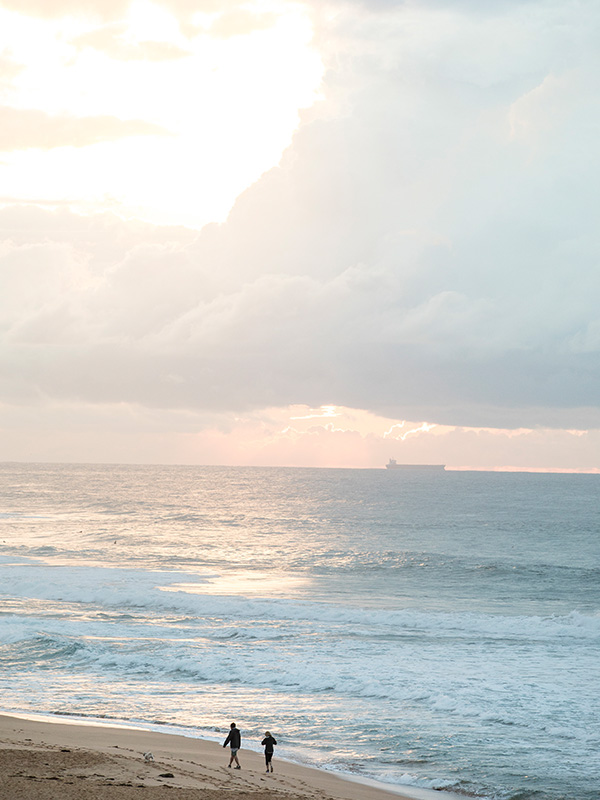 Two figures stroll along a beach in Australia