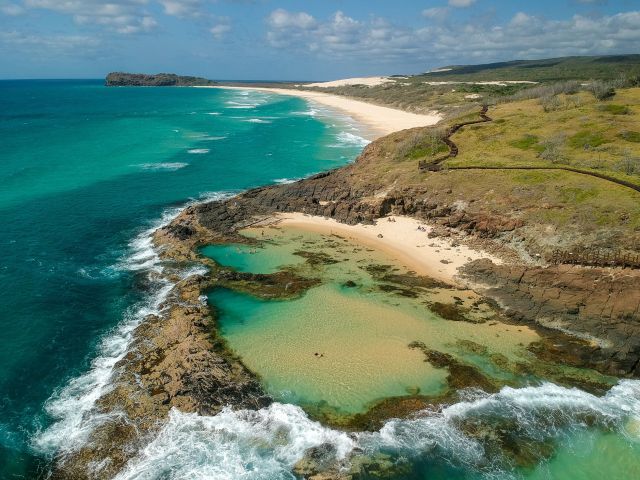 aerial of person swimming in Champagne Pools on k'gari