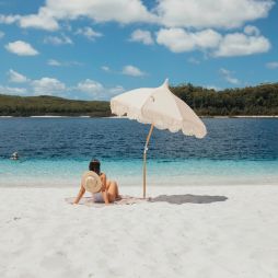 A woman relaxes on the white sand at Lake McKenzie(Image: Tourism and Events Queensland)