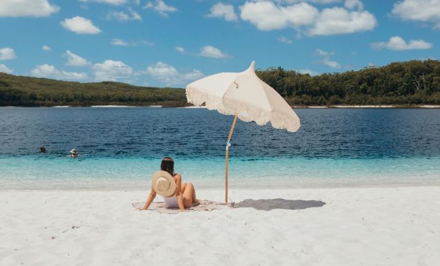 A woman relaxes on the white sand at Lake McKenzie(Image: Tourism and Events Queensland)
