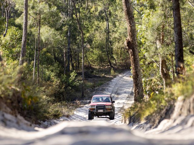 a 4wd driving on a sandy road on k'gari fraser island