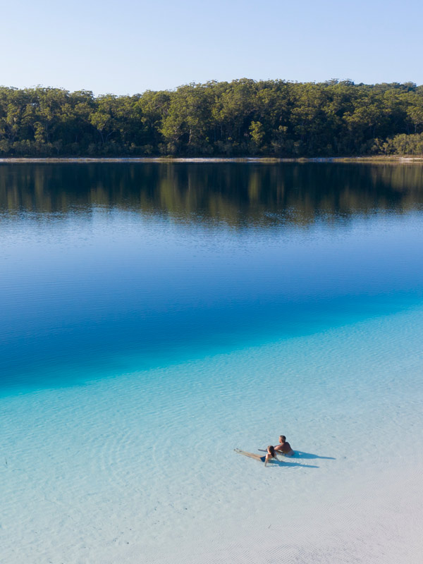 A couple sit in the water at Lake McKenzie(Image: Tourism and Events Queensland)