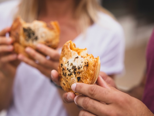 Couple enjoying pies from The Upper Crust pie shop, Collaroy (Image: Destination NSW)