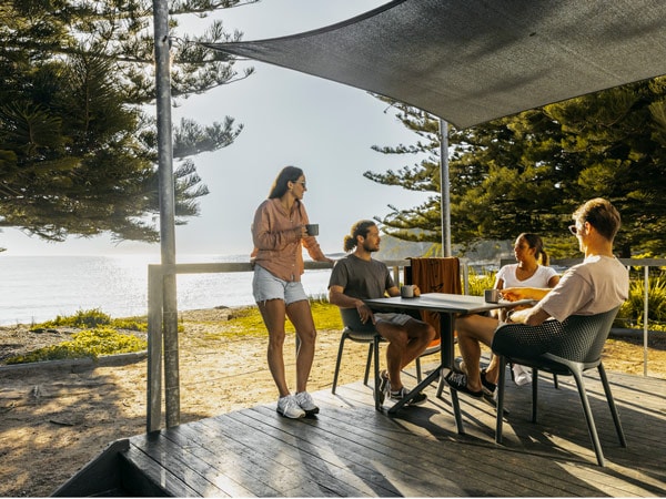 friends relaxing on the balcony of a cabin overlooking the beach at Murramarang Beachfront Holiday Resort in South Durras