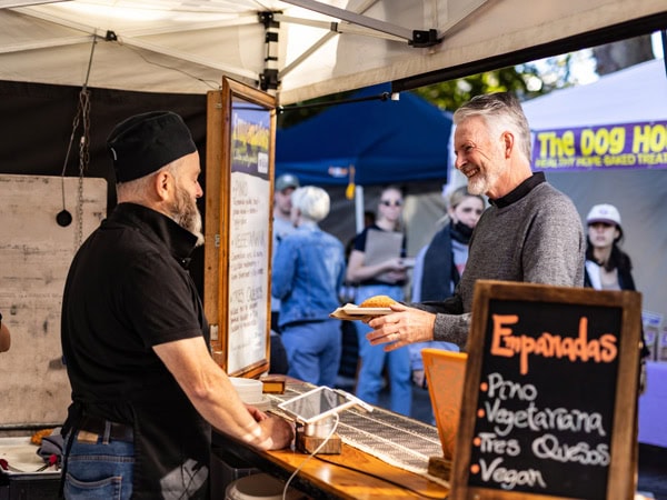 a man ordering at an empanada stall along Salamanca Market, Hobart