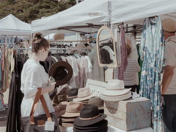 A woman shops for a hat at Terrigal Beach Markets on the Central Coast