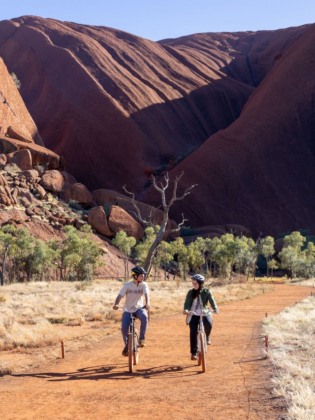Two people cycling around Uluru
