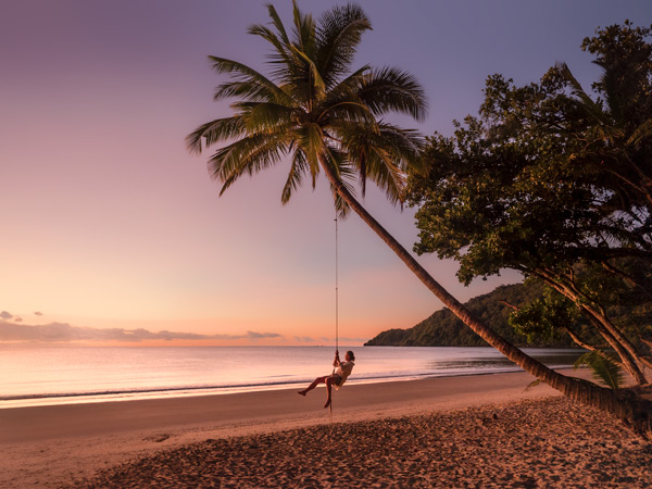 riding a swing at sunset on Cow Bay Beach