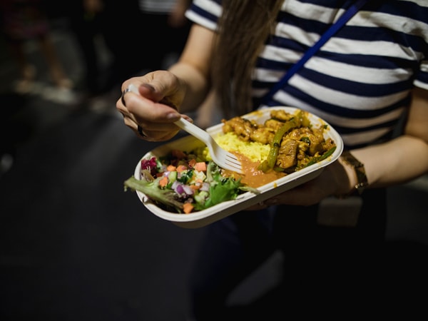 A woman eating street food at a night market in Central Coast, Australia