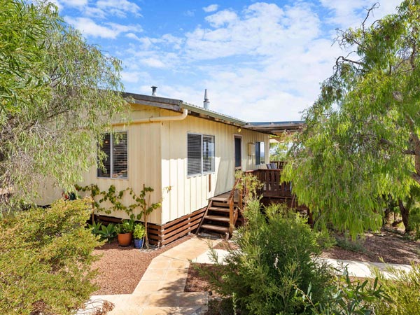 A yellow house with stairs surrounded by trees.