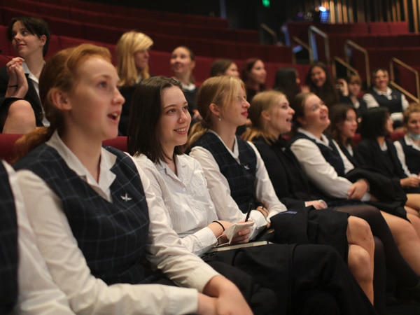 Children sitting in theatre seats and smiling.