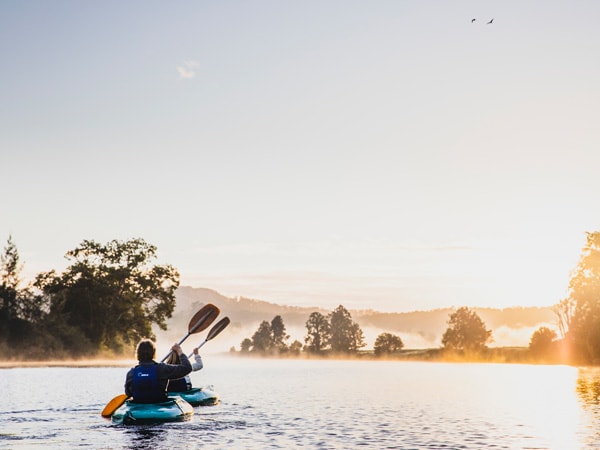 A photo of a couple on a canoe along a river.