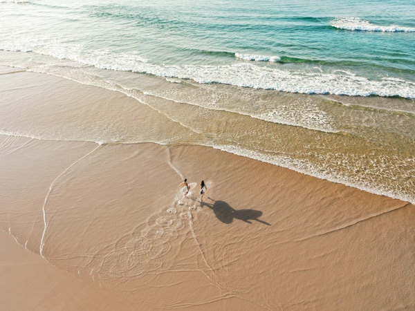 Surfers walking into the ocean at Birubi Beach