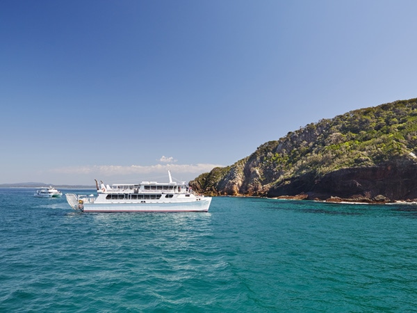 A boat in the ocean navigating to a beach.