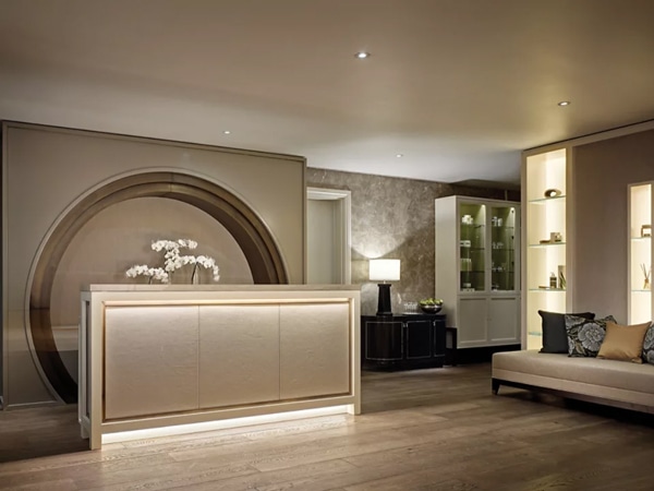 The indoors of a spa centre with a reception, bench and flowers.