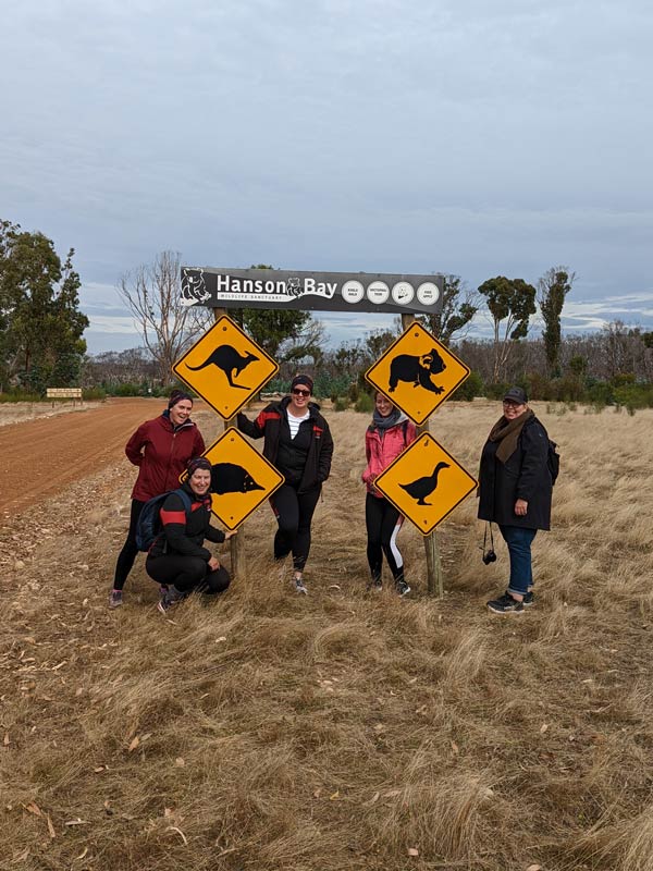 People standing in front of a sign with the animals at Hanson Wildlife Sanctuary