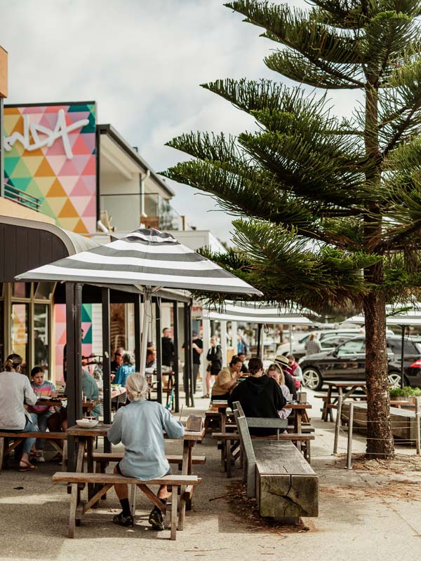 People sitting on benches drinking at a pub in Lorne.