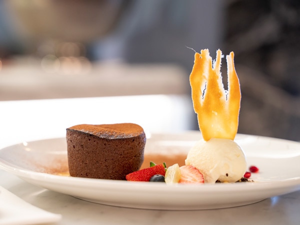 A photo of a cake, ice cream and fruit on a white plate.