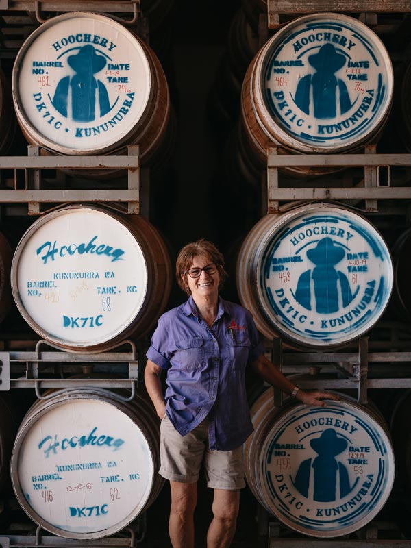 Woman standing in front of barrels at The Hoochery Distillery Cafe