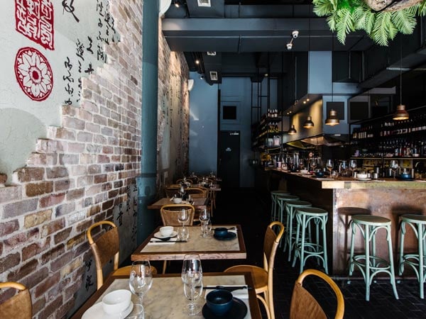 A photo of a restaurant with chairs, tables and a bar.