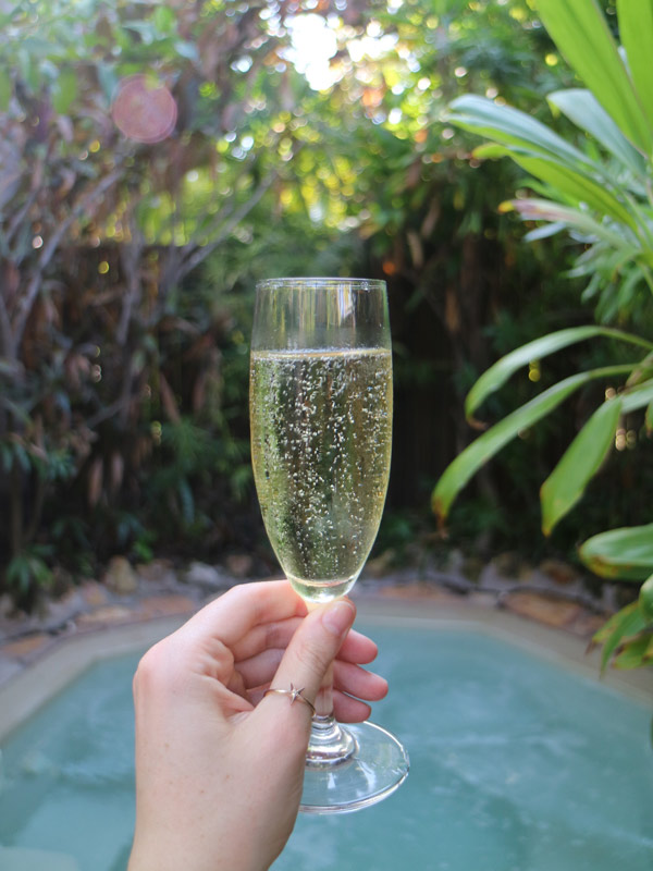 a hand holding a glass of champagne by the pool at Palms City Resort, Darwin