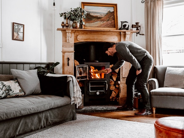 Man stokes fireplace in cosy farm stay.