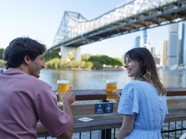 a couple drinking beer by the Story Bridge at Howard Smith Wharves
