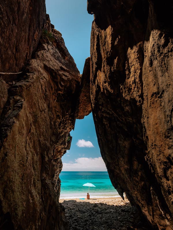 Person sitting on beach in Pelorus Island Beach Cave.