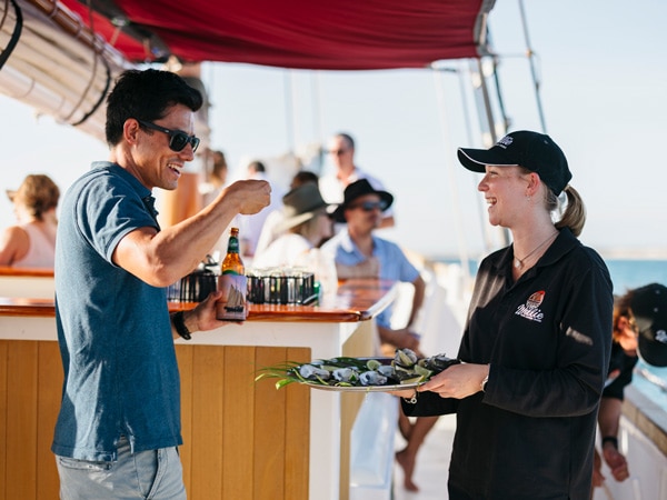 Man talking to worker on Willie Cruises serving oysters drinking a Coopers Pale Ale.