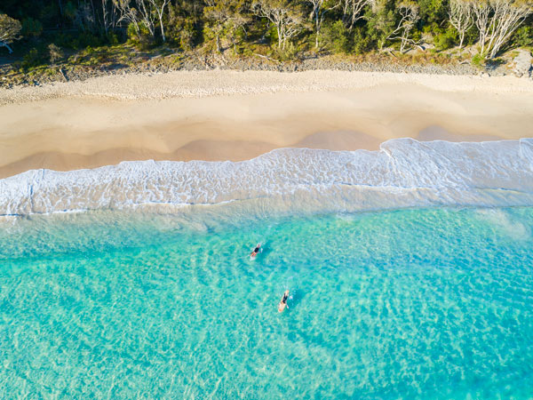 Two surfers paddling out to surf at Noosa Heads