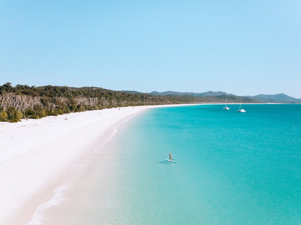 Stand up paddleboarder on Whitehaven beach - one of the best beaches in Australia