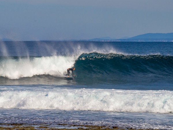 Surfer surfing waves at Wreck Bay in NSW