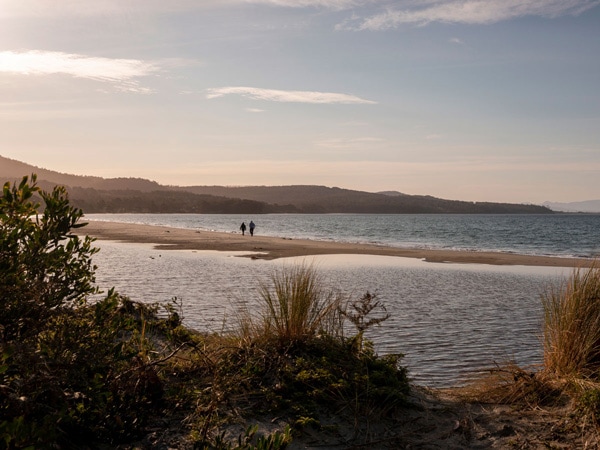 a distant shot of a couple walking along Adventure Bay