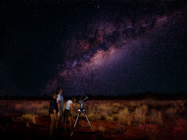 three people stargazing at night in Uluru