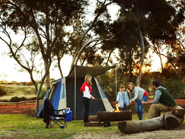 a family gathering around a bonfire setup in Voyages Ayers Rock Resort Campgrounds