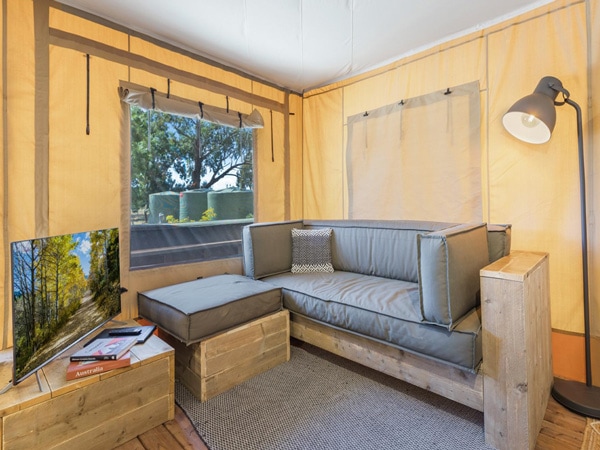 a sofa facing the tv beside an open window inside the glamping tent at BIG4 Bendigo Marong Holiday Park