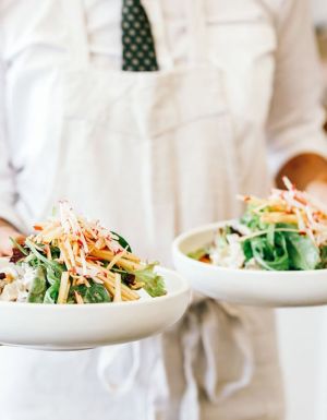 a person in white holding two plates of food at Plantation Cafe, Bowral