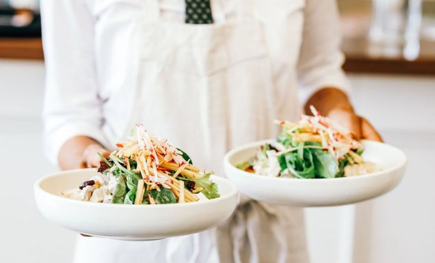 a person in white holding two plates of food at Plantation Cafe, Bowral